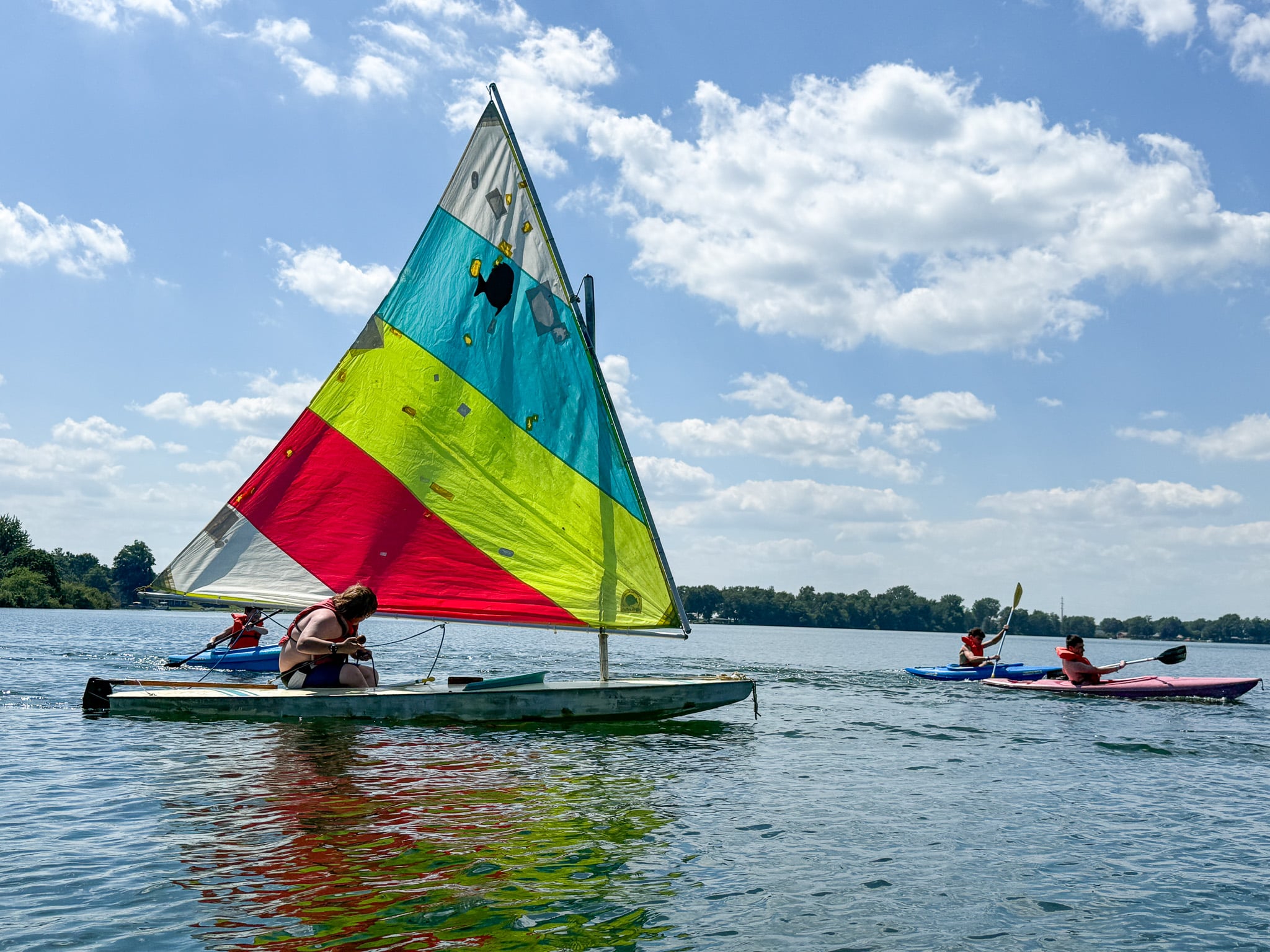 Sailboat surrounded by kayaks