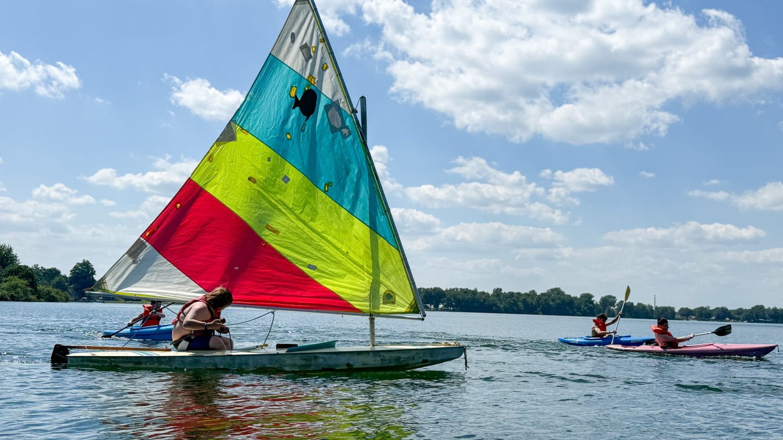 Sailboat surrounded by kayaks